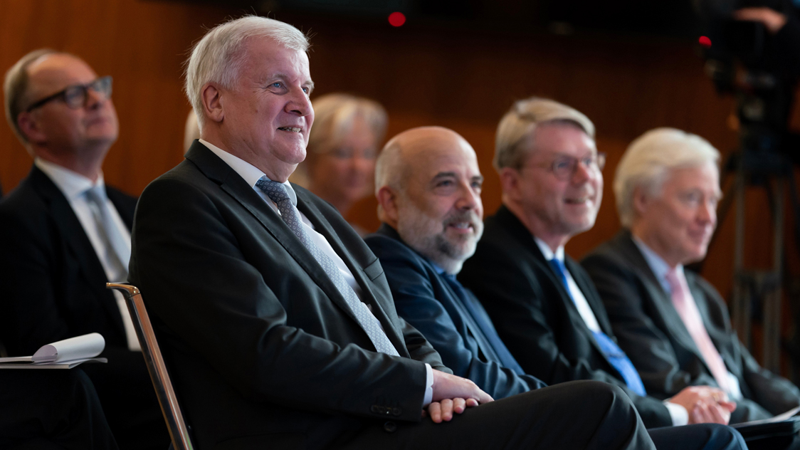 Mehrere Männer sitzen in Stuhlreihen. (Quelle: © Henning Schacht) Mehrere Männer sitzen in Stuhlreihen.