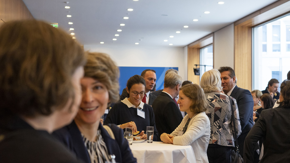 Frauen und Männer stehen an Stehtischen und unterhalten sich. (Quelle: © Annalena Sippl) Frauen und Männer stehen an Stehtischen und unterhalten sich.
