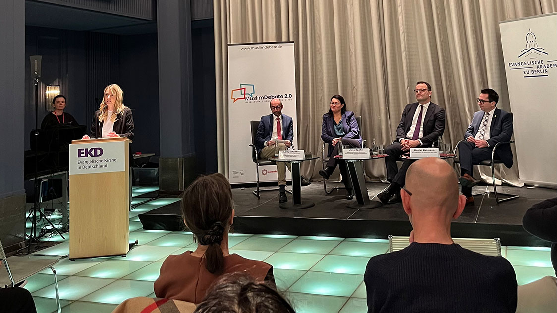 Eine Frau hinter einem Rednerpult spricht zu einem Publikum (Quelle: BAMF) Eine Frau hinter einem Rednerpult spricht zu einem Publikum