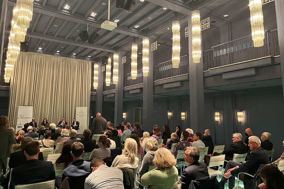 Eine Frau und drei Männer sitzen vor einem Publikum (Quelle: BAMF) Eine Frau und drei Männer sitzen vor einem Publikum