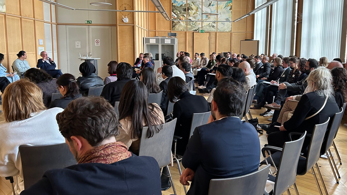 Veranstaltungsraum mit Blick aufs Podium und zahlreichen sitzenden Teilnehmenden.  (Quelle: BMI) Veranstaltungsraum mit Blick aufs Podium und zahlreichen sitzenden Teilnehmenden.