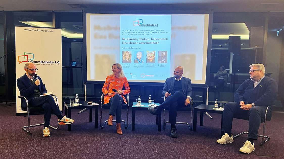 Eine Frau und drei Männer sitzen vor einer Leinwand in einem Stuhlhalbkreis. (Quelle: Shereen Sayda) Eine Frau und drei Männer sitzen vor einer Leinwand in einem Stuhlhalbkreis.