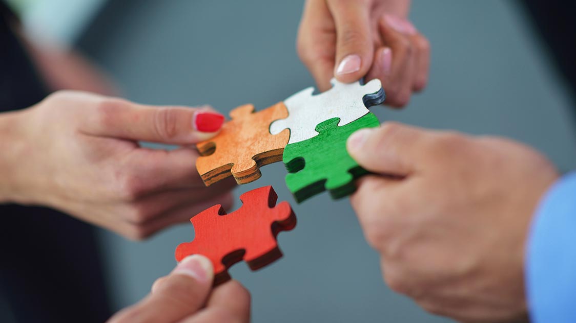 Vier Hände halten Puzzleteile (Quelle: AdobeStock | .shock) Vier Hände halten Puzzleteile