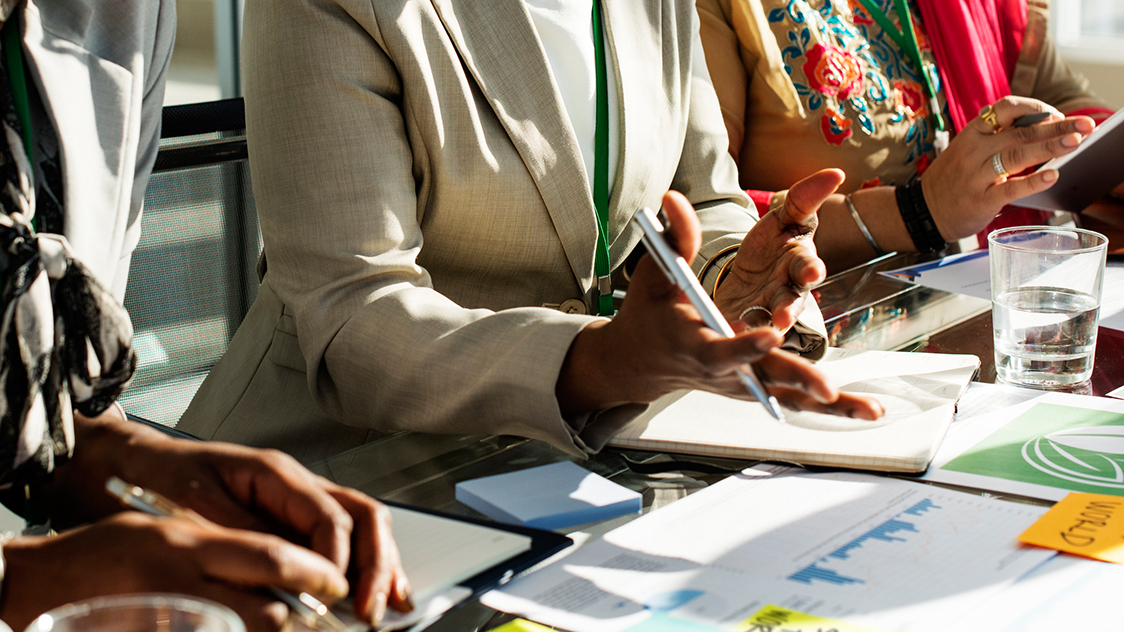 Bildausschnitt der Hände von drei Frauen an einem Konferenztisch. (Quelle: iStock | Rawpixel) Bildausschnitt der Hände von drei Frauen an einem Konferenztisch.