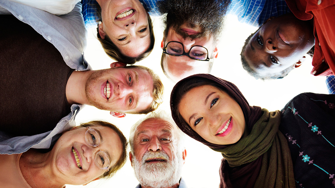 Männer und Frauen stehen in einem Kreis und schauen nach unten (Quelle: iStock - Rawpixel) Männer und Frauen stehen in einem Kreis und schauen nach unten