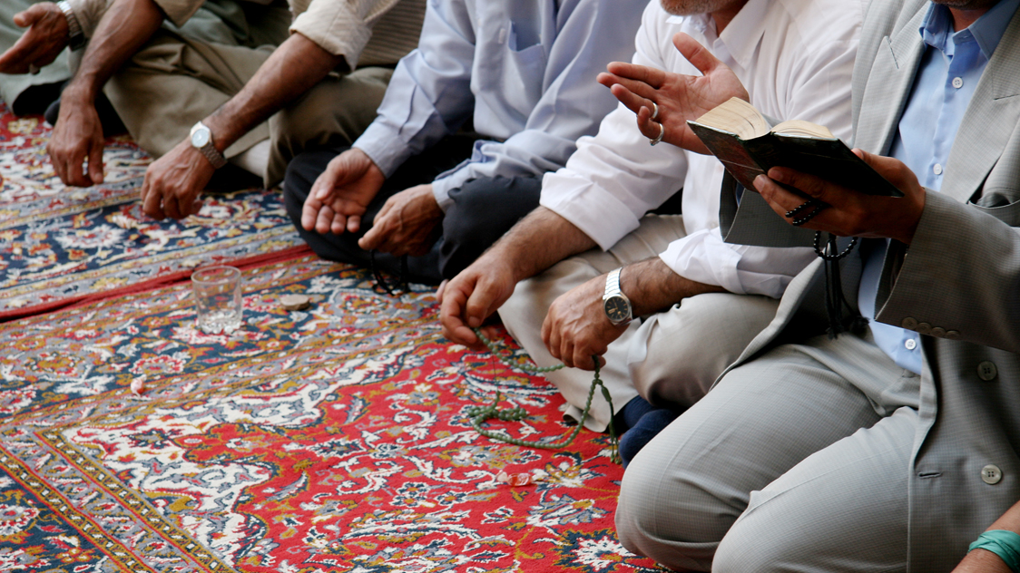 Einige Männer knien auf einem Teppich (Quelle: iStock - Scrofula) Einige Männer knien auf einem Teppich